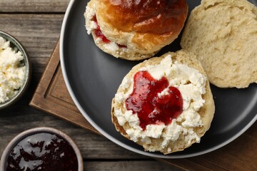 Freshly baked soda water scones with cranberry jam and butter on wooden table, flat lay