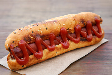 Fresh tasty hot dog with ketchup on wooden table, closeup