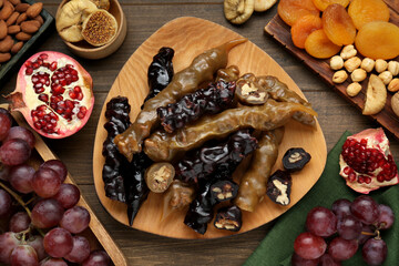 Delicious sweet churchkhelas and ingredients on wooden table, flat lay