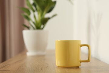 Yellow mug on wooden table indoors. Mockup for design