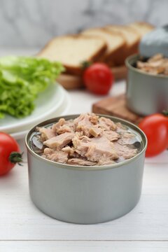 Tin can with canned tuna on white wooden table