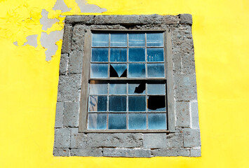Yellow wall and window with broken glass