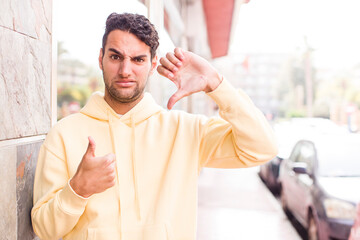 young hispanic man feeling confused, clueless and unsure, weighting the good and bad in different...