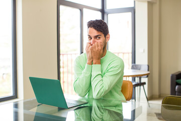 young hispanic man looking worried, anxious, stressed and afraid, biting fingernails and looking to lateral copy space. working at home