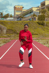 Mujer afro bailarina realiza baile en parque local en la pista de atletismo con hermosa vegetacion y cielo de fondo