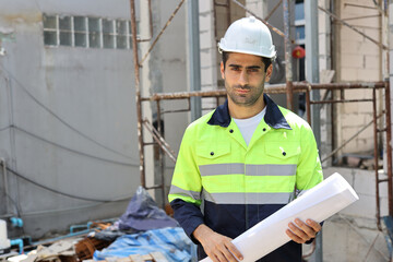 Caucasian technician civil engineer man or specialist inspector standing and planing real estate project work with blueprint while checking at Industrial building site. Construction concept