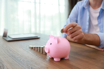 Obraz na płótnie Canvas Businessman hand putting coin into piggy bank with saving growth on stacking coin growing, meaning of earning money or investment or financial or tax for business advertising concept