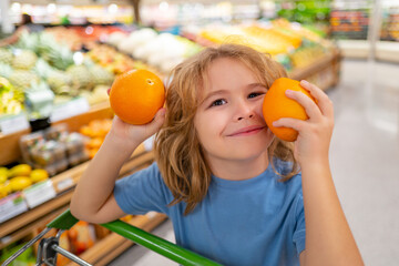 Cute child hold shopping cart full of groceries. Kid holds shopping basket. Store, shopping, sales...