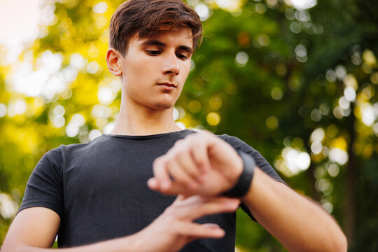 Runner on mountain trail looking at smartwatch or sport watch, checking gps navigation position map or heart rate pulse trace, using heart monitor equipment. Sport and fitness outdoors in nature.