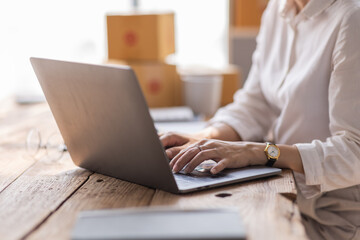 Asian SME business woman using laptop computer Phone checking customer order online shipping boxes at home. Starting Small business entrepreneur SME freelance. Online business, Work at home concept.