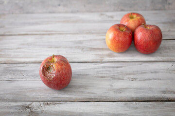 A red rotten disgusting apple separated of good ones. Bad and good separated.