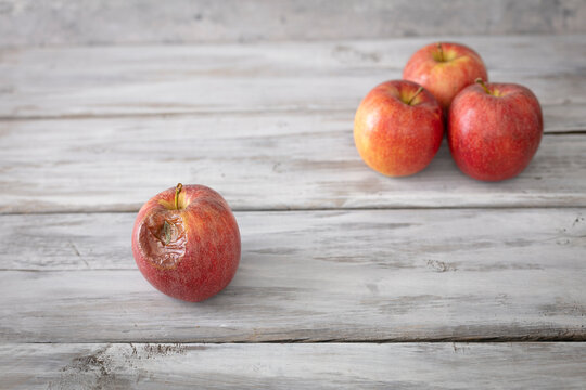 A red rotten disgusting apple separated of good ones. Bad and good separated.