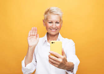 mature lady taking a selfie on yellow background