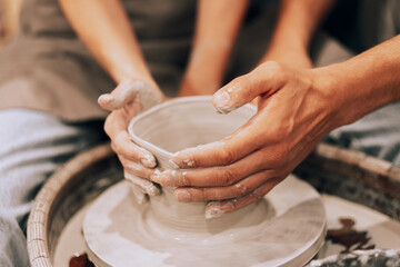 Couple mold ceramic vase in a pottery workshop, hands close up.