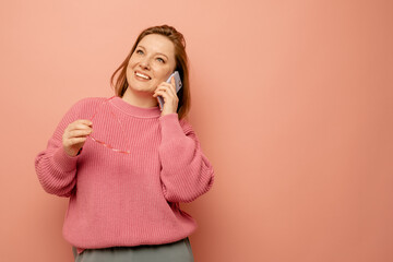 cheerful woman talking on mobile phone over pink background