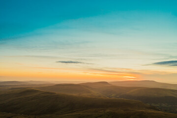 Welsh landscape under a colorful sunset showcasing rolling hills and a tranquil sky