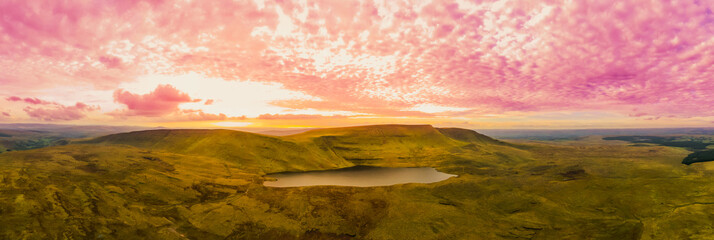 Breathtaking sunset over the rugged landscape and serene lake in Wales, capturing the vibrant colors of twilight on a tranquil evening