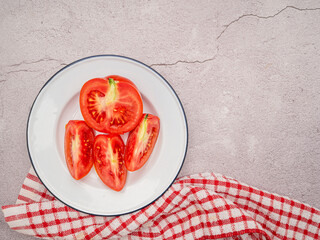 Fresh tomatoes on a white plate with a cloth on a table