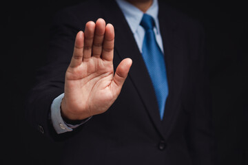 Businessman shows a stop gesture while standing on a black background