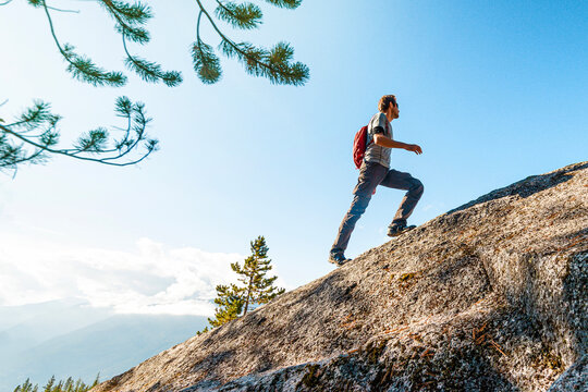 Challenges, success and accomplishment in business and life. Aspirational conceptual image of fit male hiker man climbing and hiking steep mountain in uphill climb