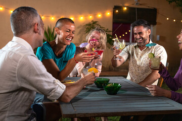 Group of friends enjoying some cocktails after dinner outdoors in the garden. Having fun together and laughing,