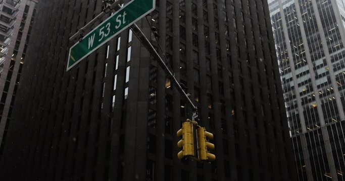 Snow on the street with a traffic light and a sign in front of skyscrapers in Manhattan, New York.