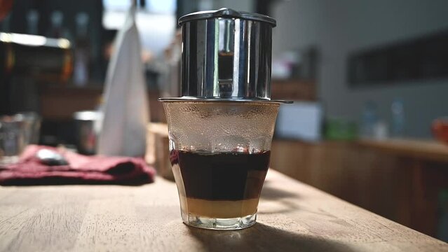 Vietnamese black coffee brewed in French drip filter on wooden table