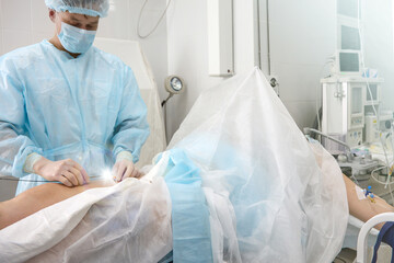 Patient lying behind screen operating table, experienced phlebologist conducts radiofrequency...