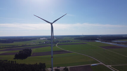 Wind turbines in a farm field up close with a drone point of view. Over 100 meters tall.