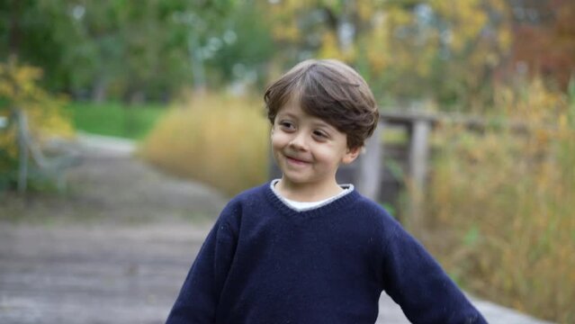 Portrait of a happy child walking outside at park. One cute little boy face smiling outdoors during autumn season