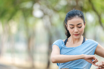 Asian woman stretching body and neck after jogging exercise at park in the city. Attractive athlete girl in sportswear enjoy outdoor lifestyle sport training fitness running workout in morning summer