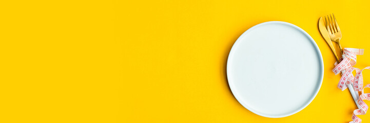 Minimal macro photography of measuring tape on fork and knife on yellow background with copy space....
