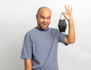 Naklejka premium Handsome young man smiling and happy with protection mask. Charming male standing with on isolated white background. Asian people pose with white backdrop.