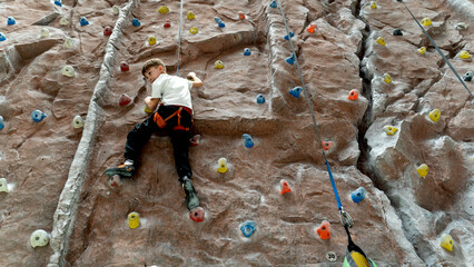 a boy on a climbing wall climbs up the wall