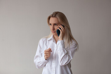 A young woman in a white shirt talking on the phone. White background.