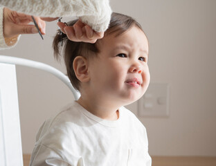 Mother cuts a boy's hair with a thinning scissors