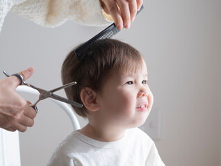 Mother cuts a boy's hair with a thinning scissors