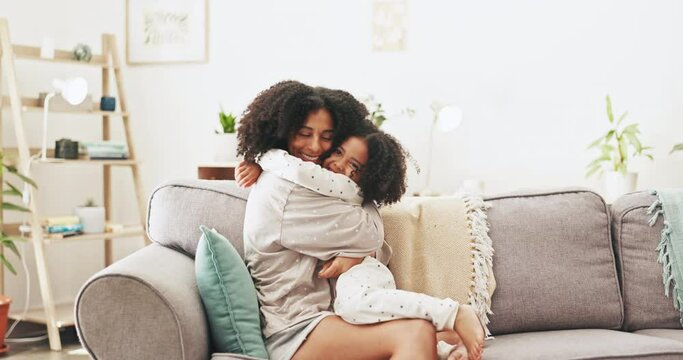 Love, happy and mother hugging her child while relaxing on a sofa in the living room of their home. Happiness, bonding and young mom embracing and kissing her girl kid with care in their family house