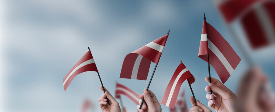 A group of people holding small flags of the Latvia in their hands
