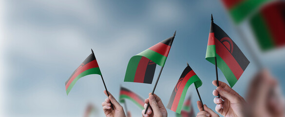 A group of people holding small flags of the Malawi in their hands