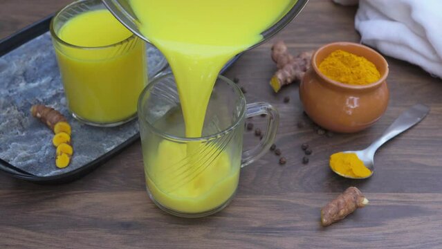 Pouring turmeric milk into a mug. Healthy detox hot drink.