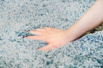 woman chooses carpet. Hand touches soft carpet in a store, close-up
