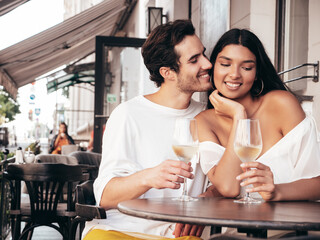 Smiling beautiful woman and her handsome boyfriend. Happy cheerful family. Sexy couple cheering with glasses of red wine at their date in restaurant. Drinking alcohol at veranda cafe