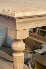 Wooden dining table with carved leg of solid oak and metal frame build process in workshop close up...
