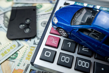 blue toy car with real keys calculator over us dollar banknotes