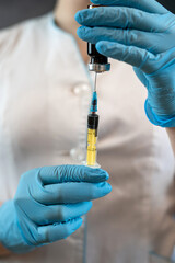 female nurse or intern in uniform, gloves mask and hat holding syringe with vaccine