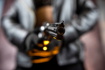 slim woman in a black jacket holding gun