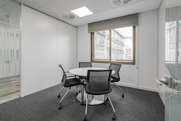 Fototapeta na wymiar Room with a round table and chairs in gray tones in an office meeting room with a large window. Concept of the director's office or the office of senior managers