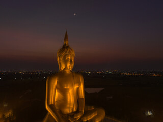 aerial view The moon on the head of golden big Buddha. 
the Biggest Buddha in the world at wat Maung Angtong Thailand.
scenery sky in twilight background.the one famous landmarks in Thailand.
