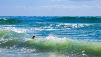 Happy girl ejnoy catching waves at beautiful intimate second bay near Coolum beach, Sunshine Coast, Queensland, Australia